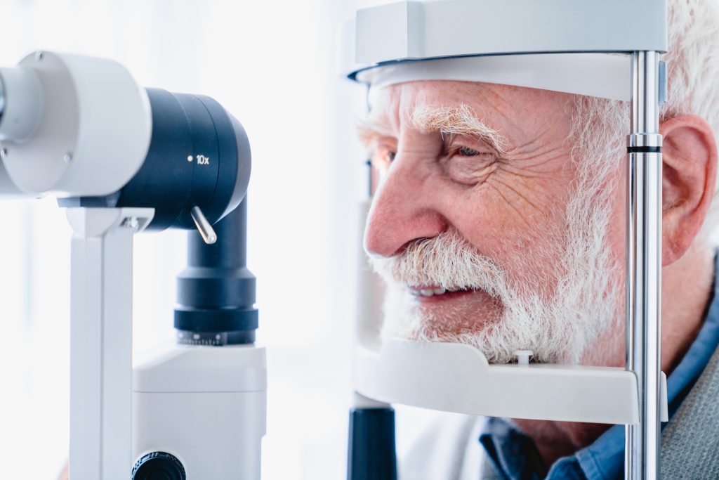 Cropped photo of happy senior patient being diagnosed with ophthalmic equipment