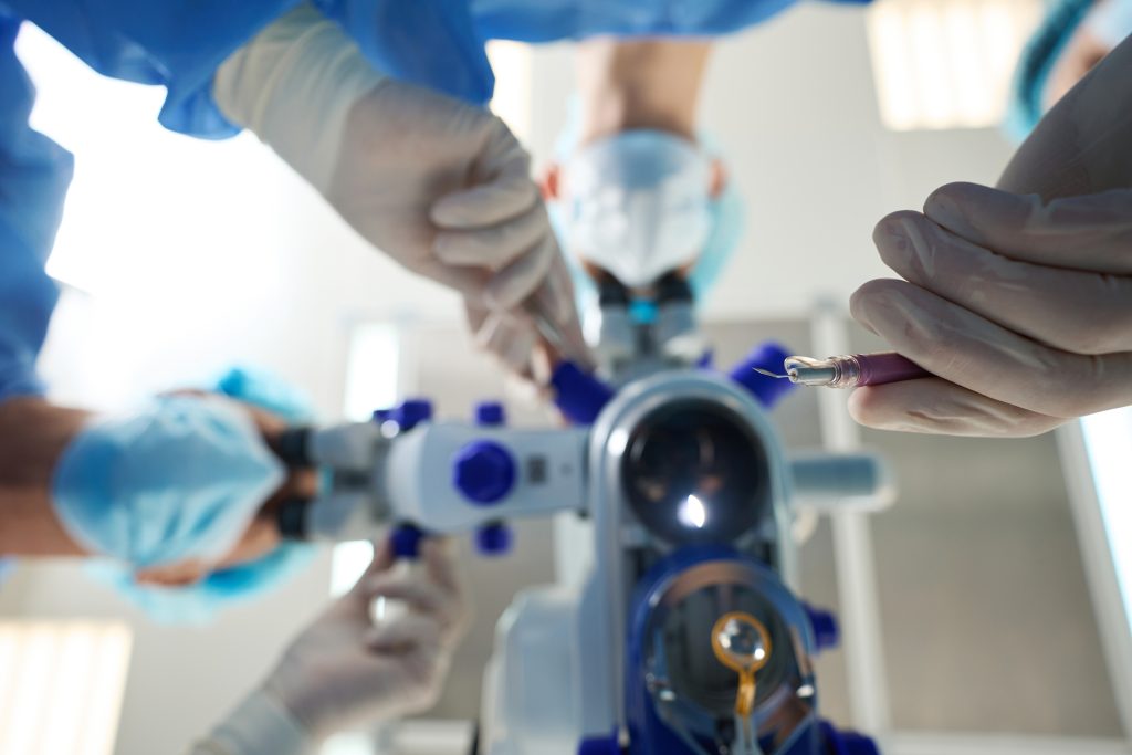 Bottom view, doctors in protective suits and masks holding medical instrument and perform an operation