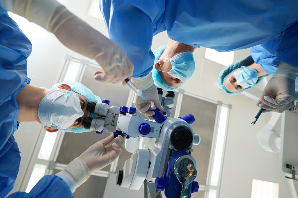 Doctors and nurse in protective suits and masks holding medical instrument and perform an operation